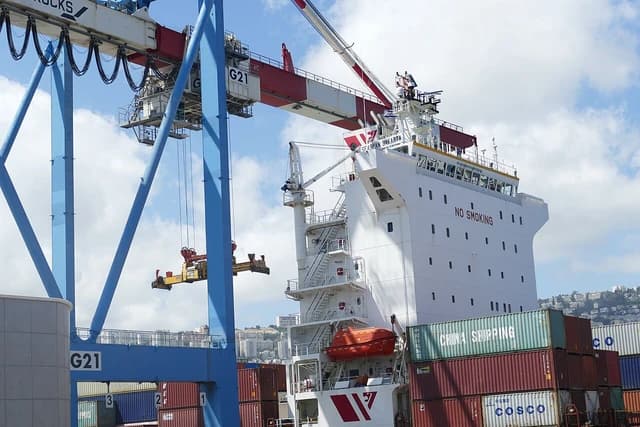 Cargo ship being loaded or unloaded at Haifa Port by large port cranes.
