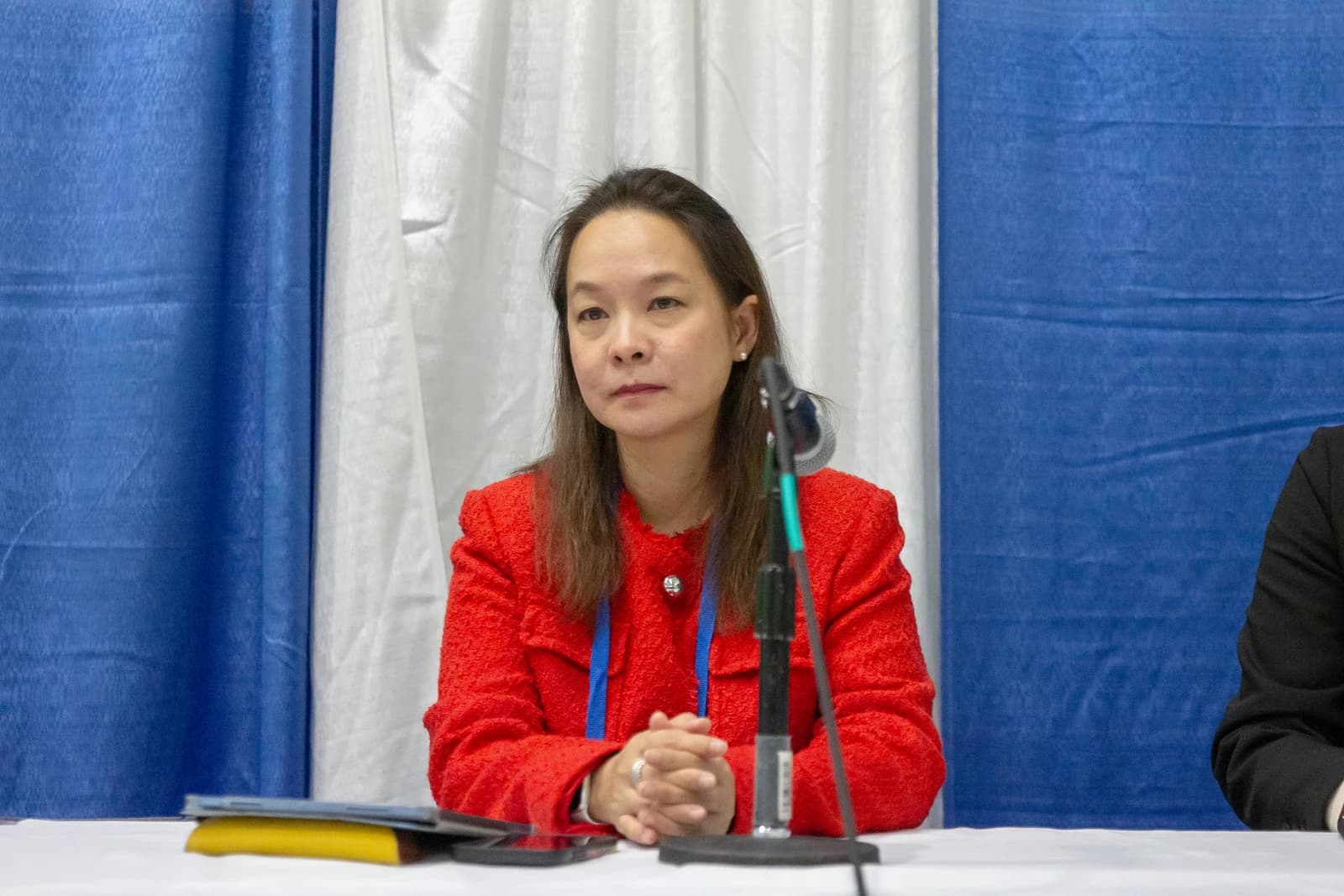 Orakanoke Phanraksa, Thai scientist, sitting at a table with a microphone.
