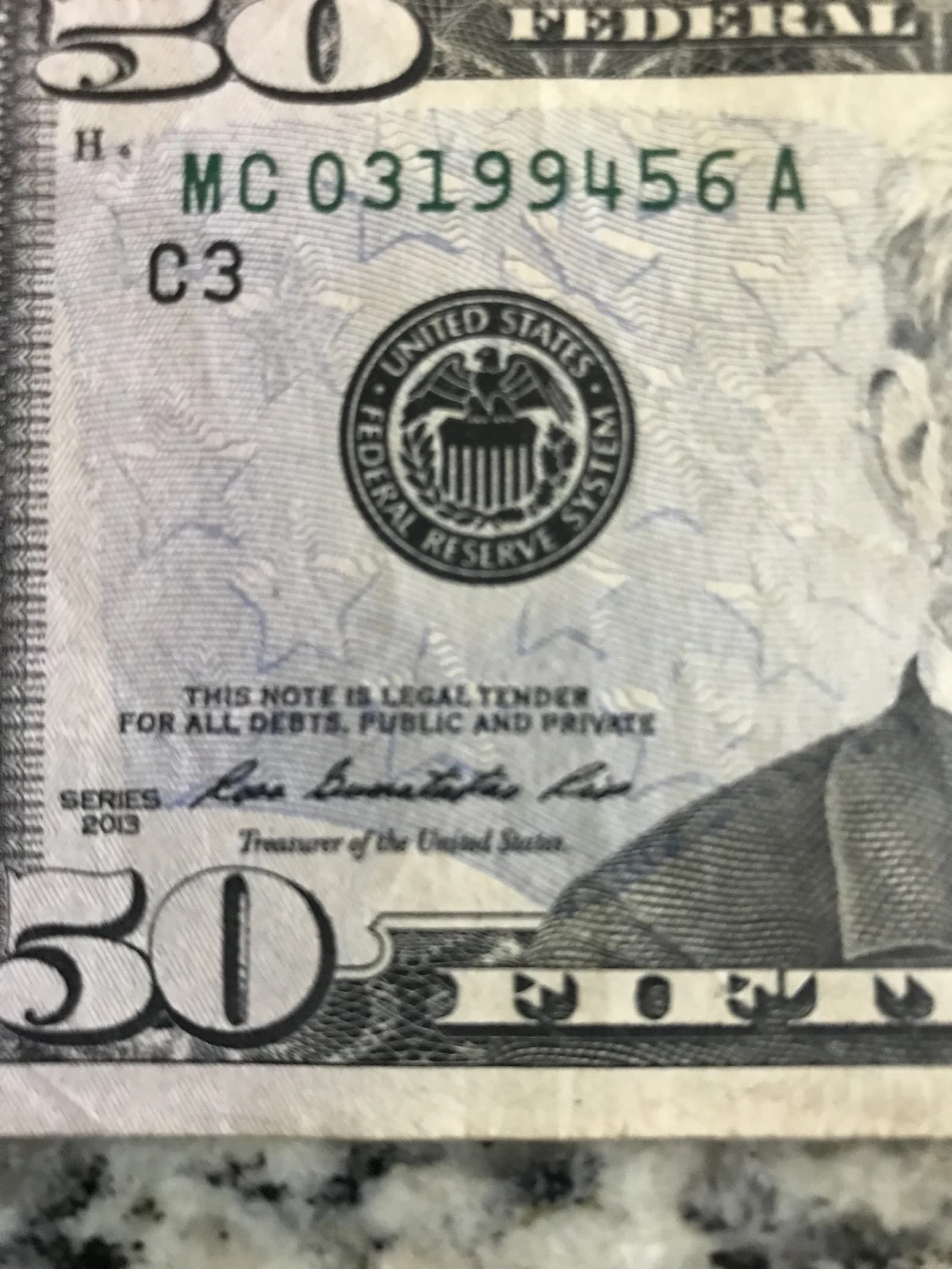 Close-up of a United States fifty-dollar bill with Federal Reserve seal.