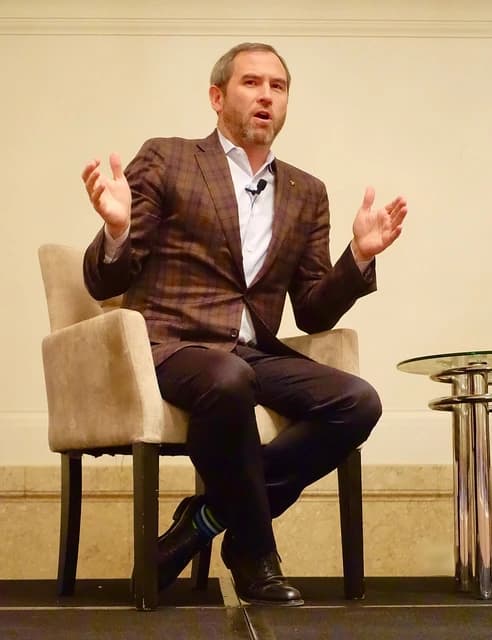 Brad Garlinghouse, CEO of Ripple, speaking at an event with his hands gesturing.