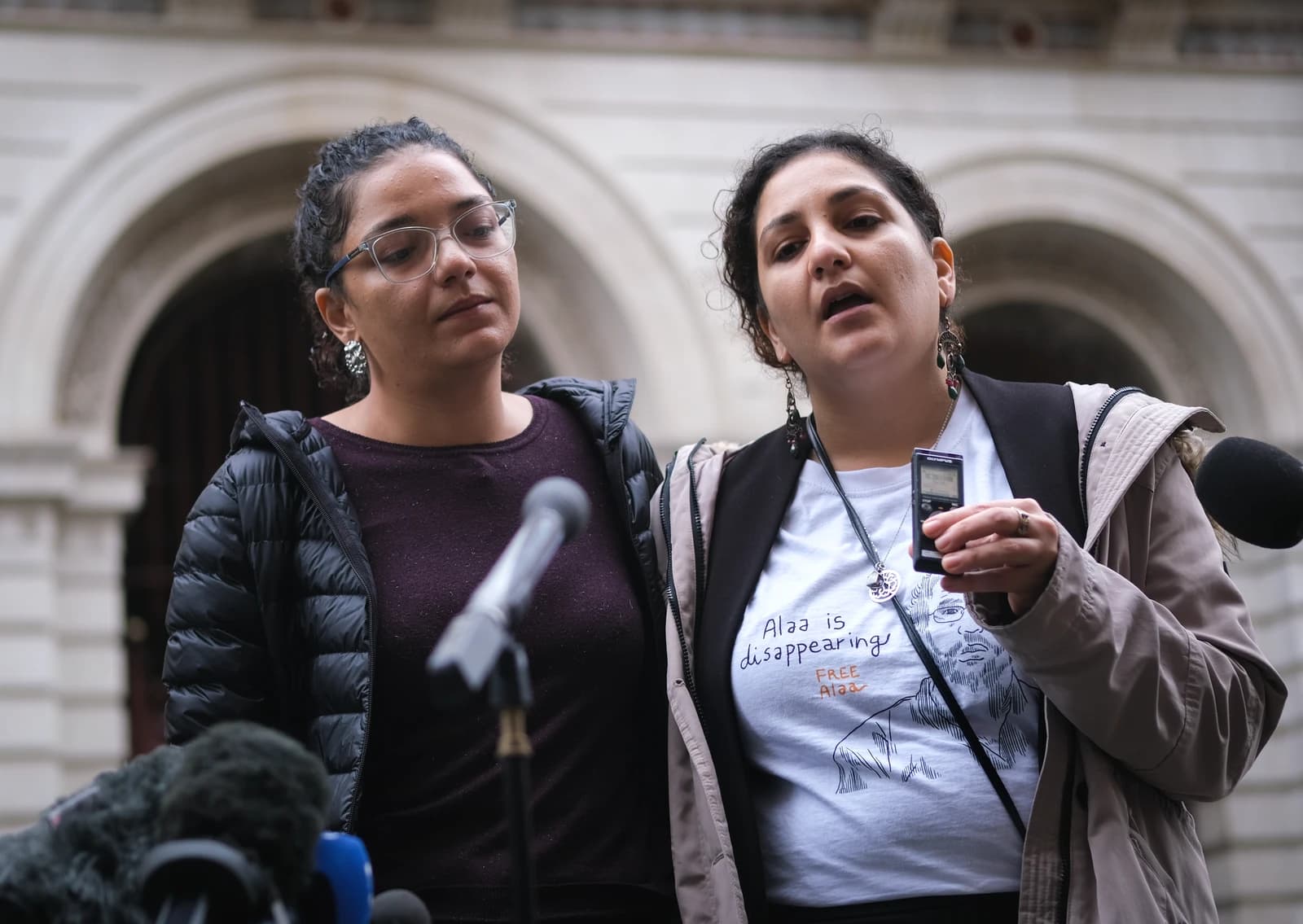 Mona Seif and Sanaa Seif addressing reporters with microphones in front of them.