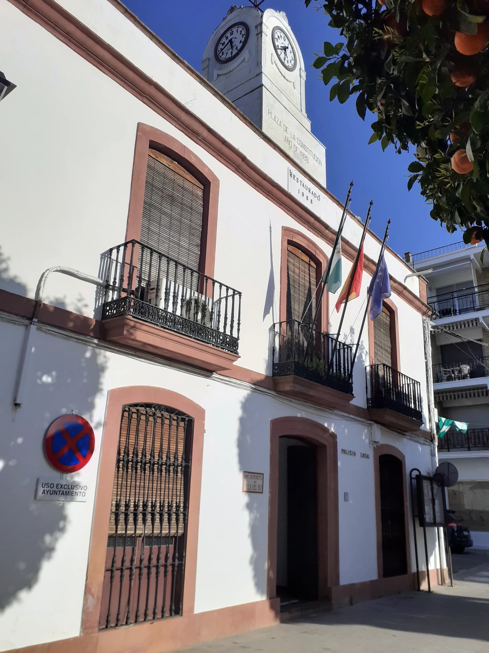 Exterior view of the Villa del Río municipal building with clocks and flags.