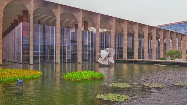 The Palácio do Itamaraty, a modern building with arches and glass, reflected in a large pool.