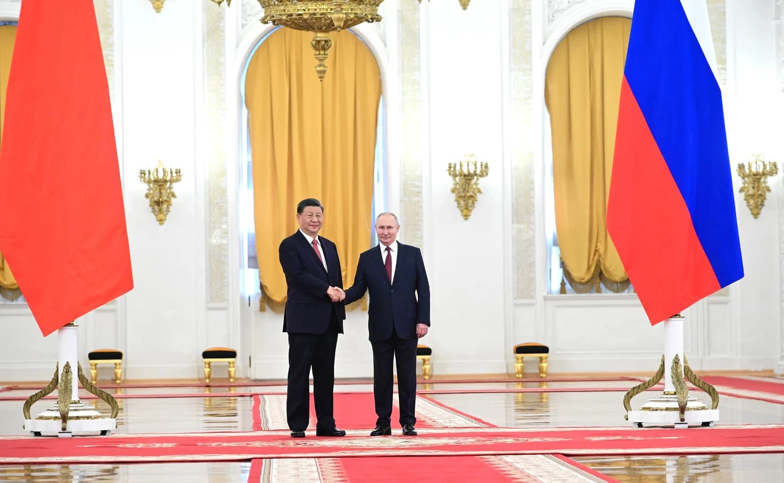 Chinese President Xi Jinping and Russian President Vladimir Putin shaking hands in a formal hall.