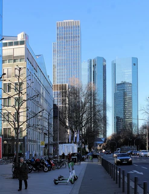 Skyscrapers, including the Deutsche Bank Twin Towers, visible from a city street in Frankfurt.