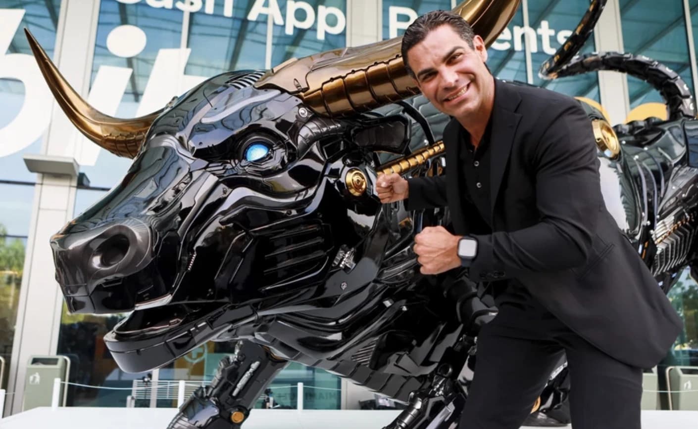 Francis Suarez, Mayor of Miami, posing next to a large robotic bull sculpture.