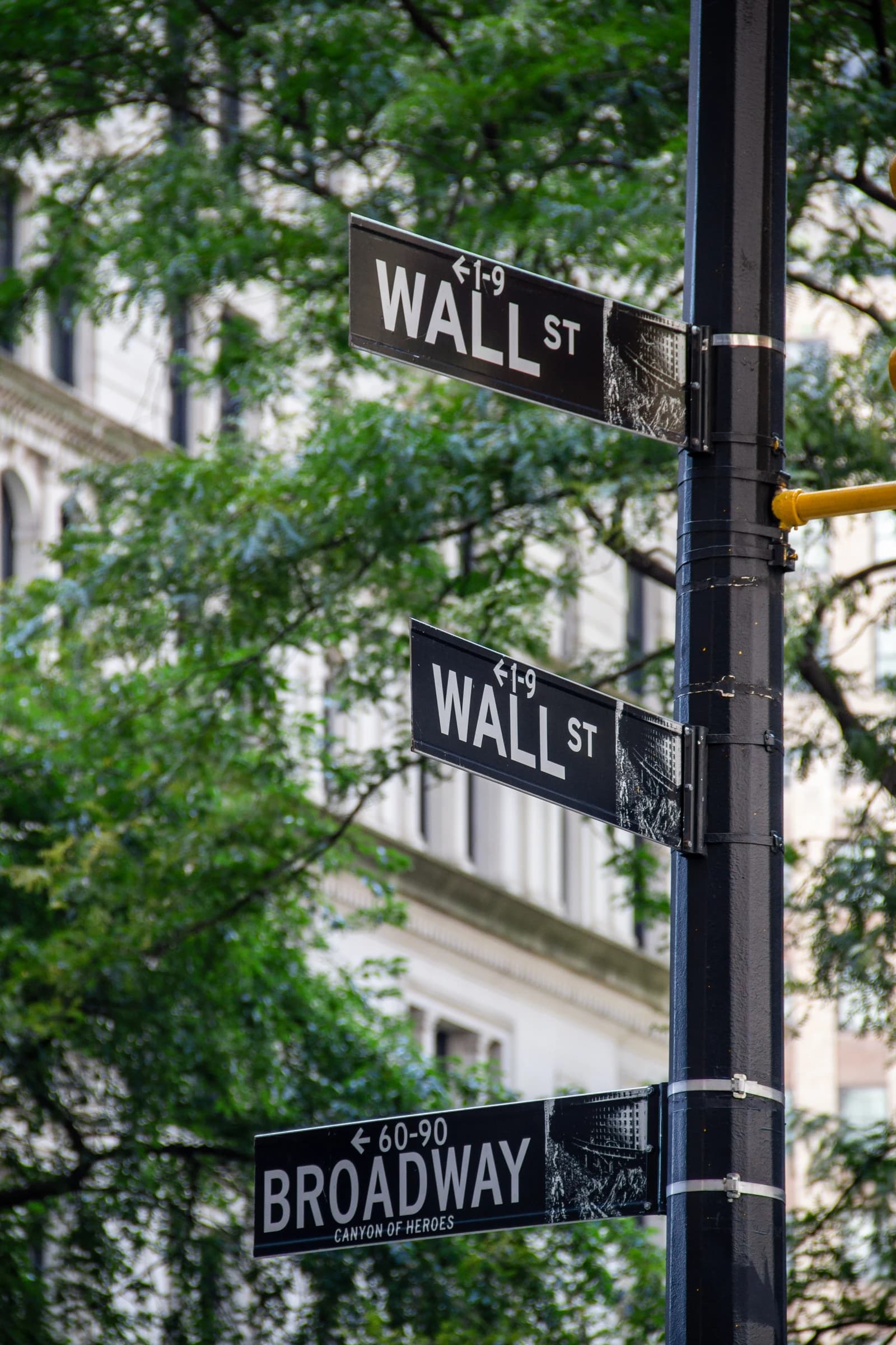 Wall Street and Broadway street signs on a lamppost in New York City.