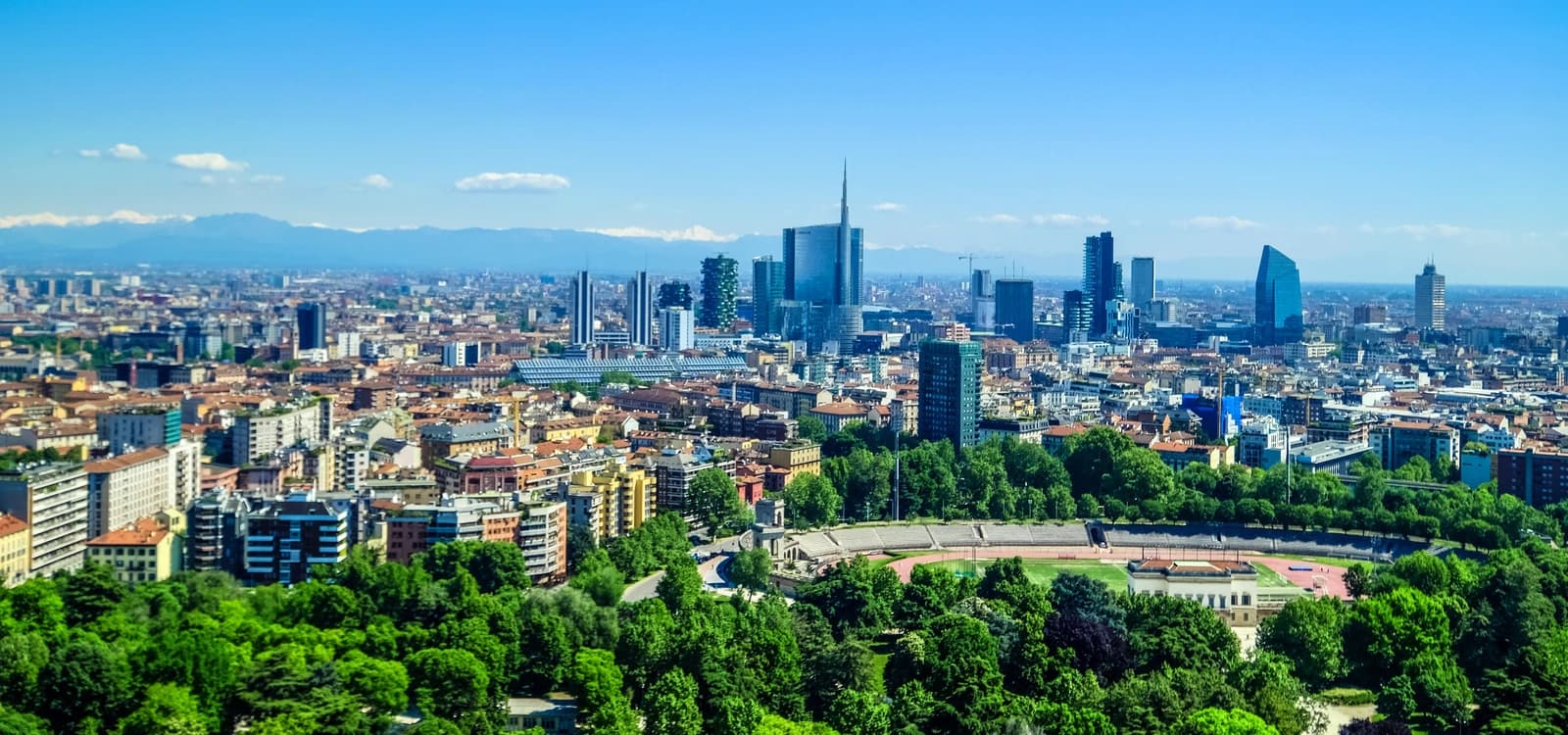 Panoramic view of Milan skyline showing modern skyscrapers and older buildings under a clear sky.