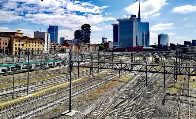 Milan Porta Garibaldi railway station and the financial center skyline under a blue sky.