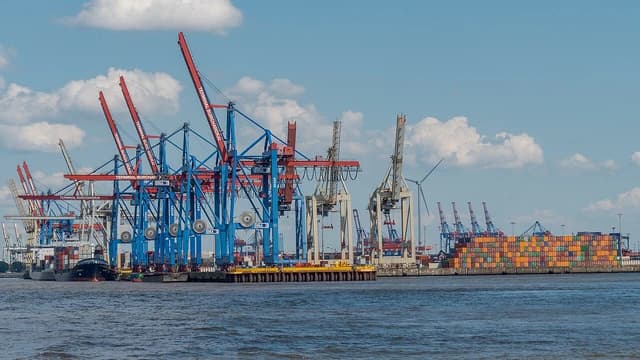 Shipping container cranes at the Terminal Burchardkai in Hamburg, Germany, overlooking the water.