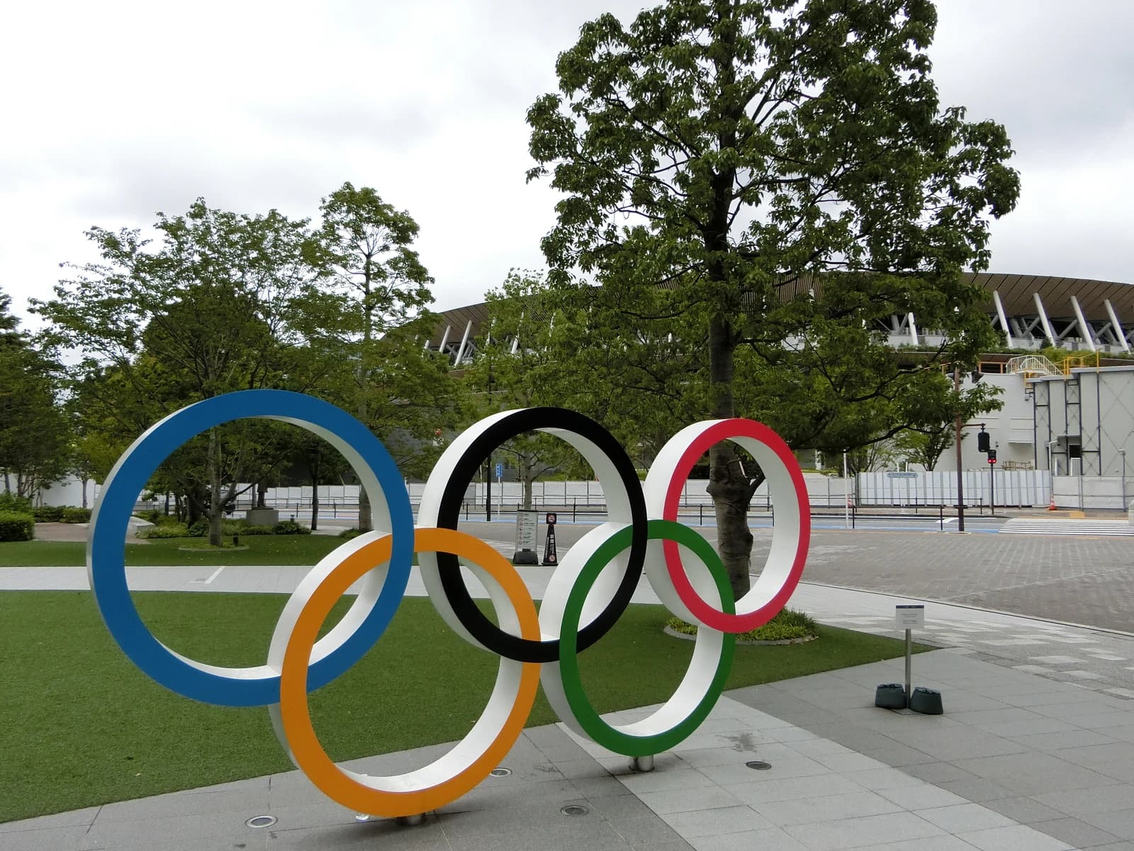 Olympic Rings sculpture with the Tokyo Olympic Stadium partially visible in the background.