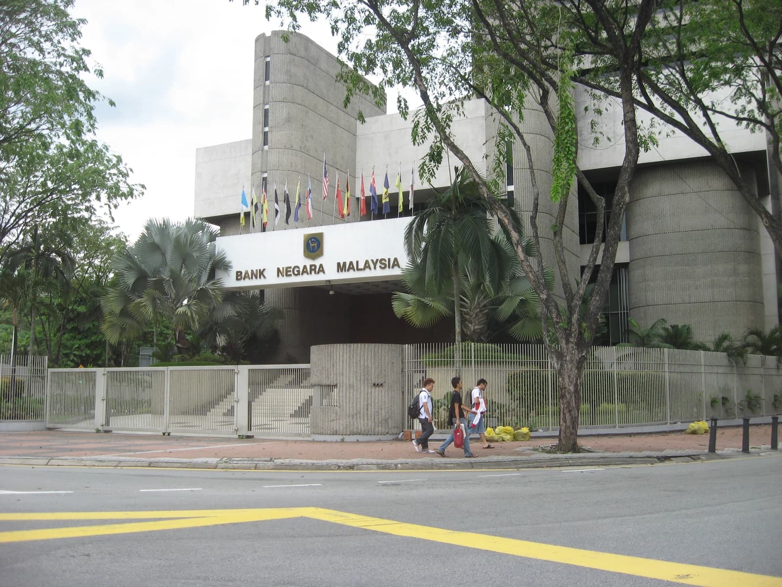 Bank Negara Malaysia headquarters building with a sign above its entrance and flags on display.