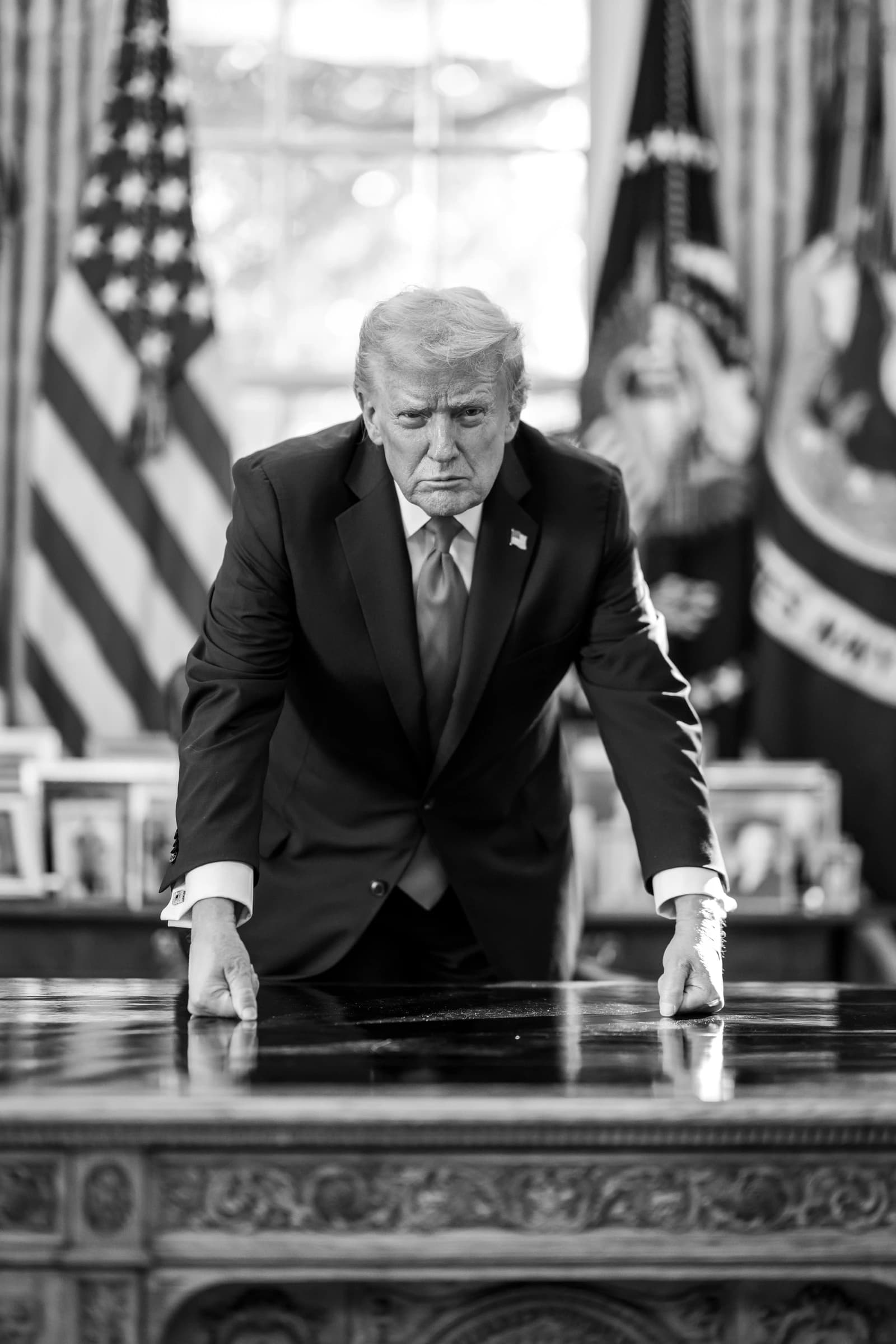 Donald Trump, former President of the United States, stands behind a desk in a formal room.
