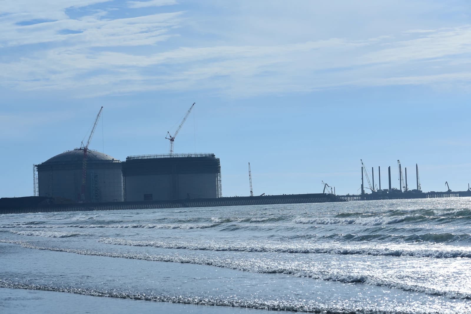 Guantang LNG port terminal construction site with large storage tanks and cranes.