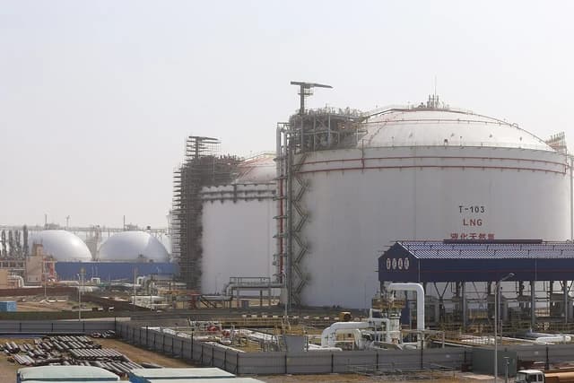 Massive white liquefied natural gas storage tanks at an industrial facility.