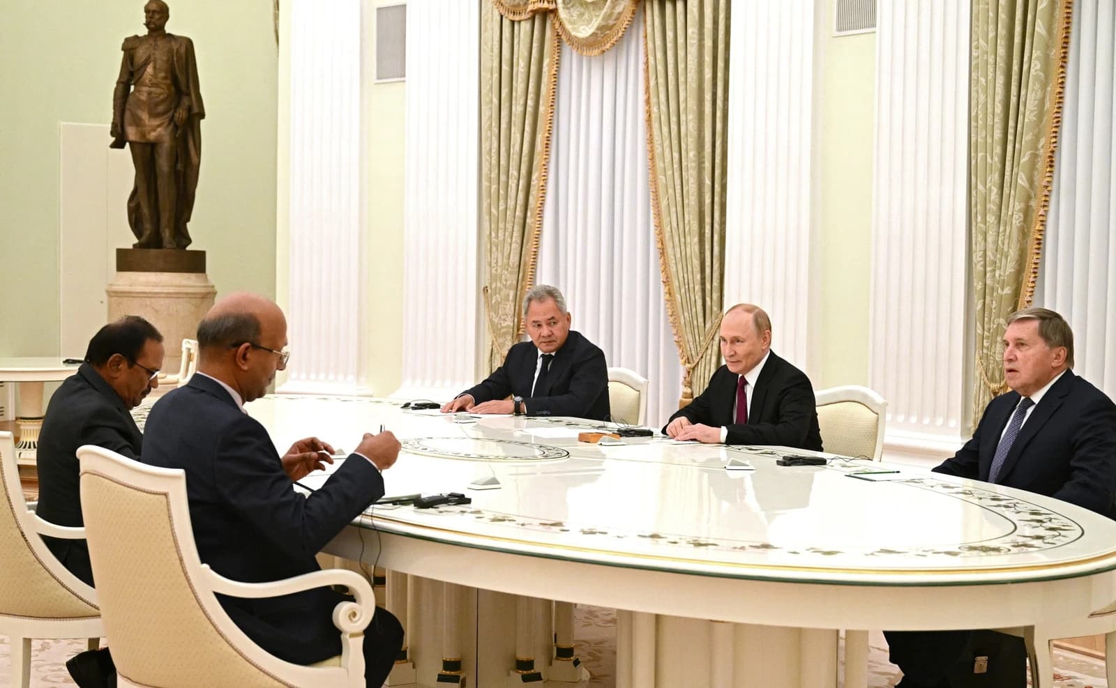 Vladimir Putin, President of Russia, seated at a long table with other officials in the Kremlin.