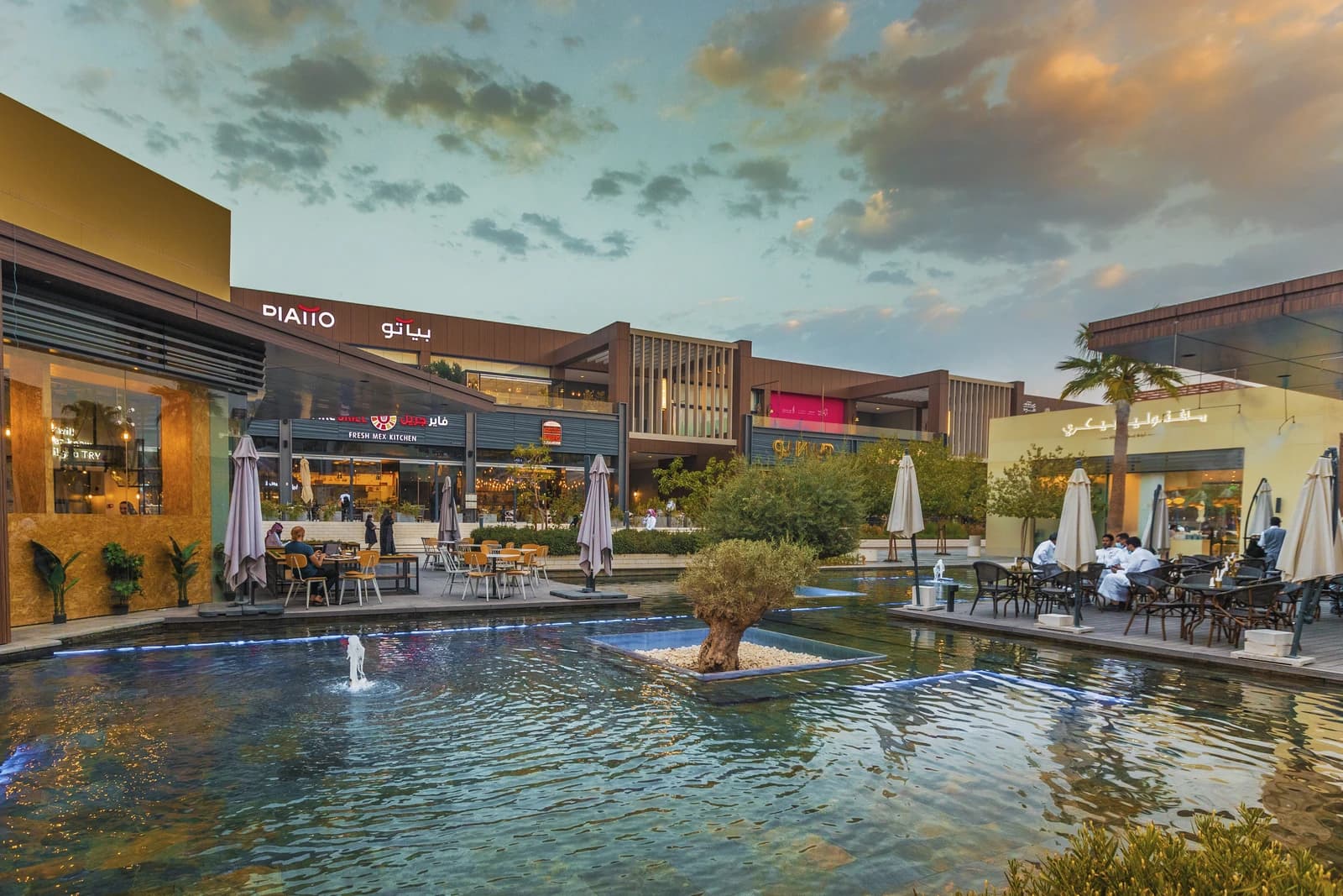 Riyadh Front Shopping Area with modern buildings, restaurants, and people dining outdoors.