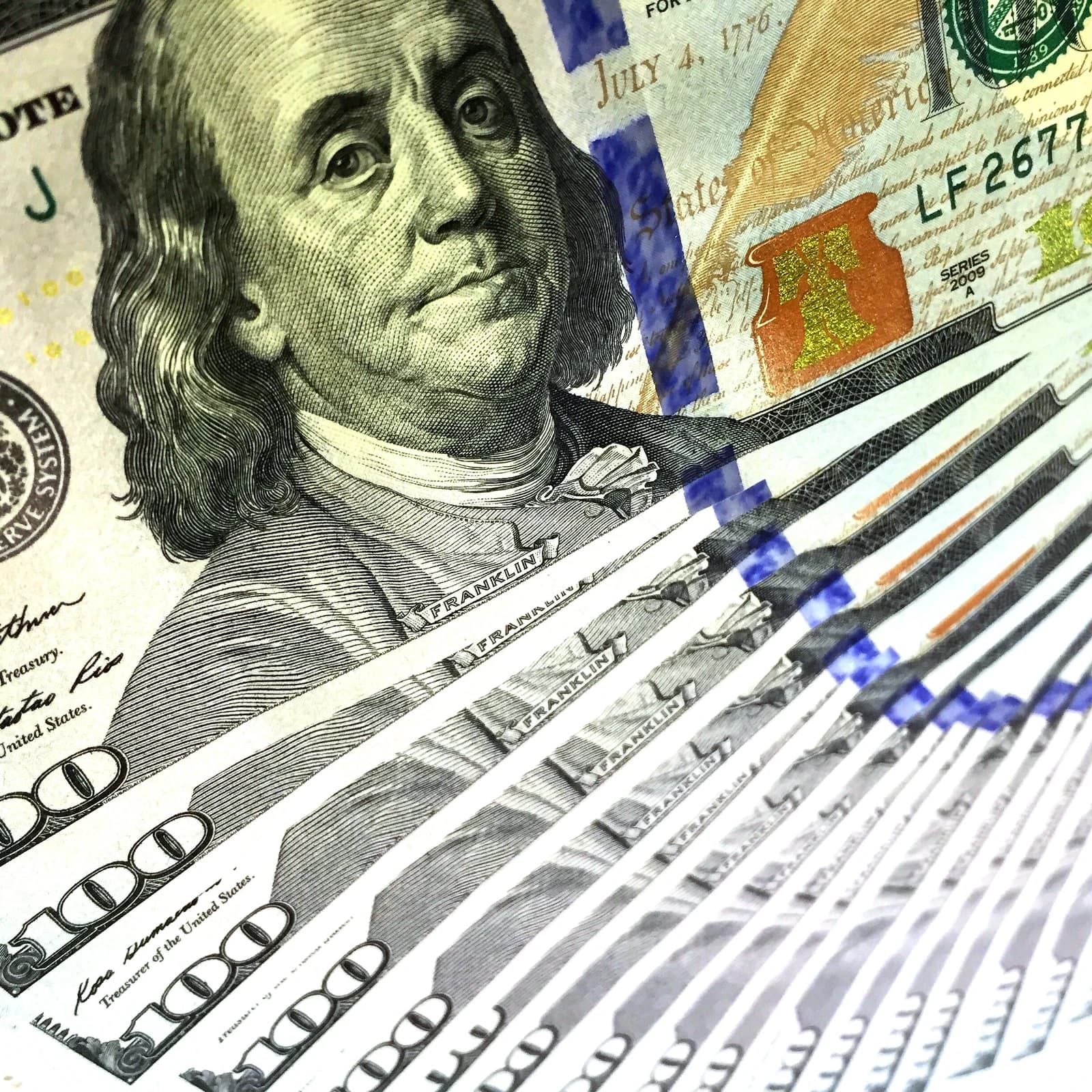 Close-up of one hundred U.S. dollar bills fanned out, featuring Benjamin Franklin.