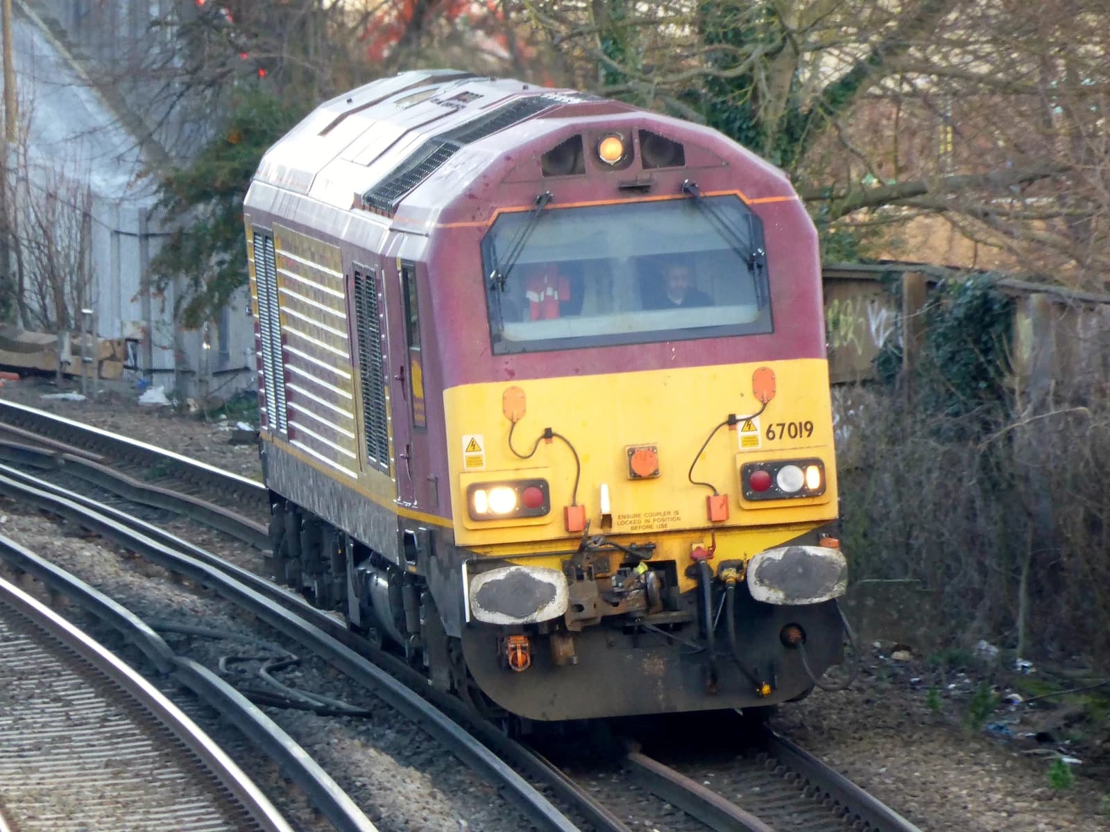 A maroon and yellow Class 67 locomotive, number 67019, on a railway track.