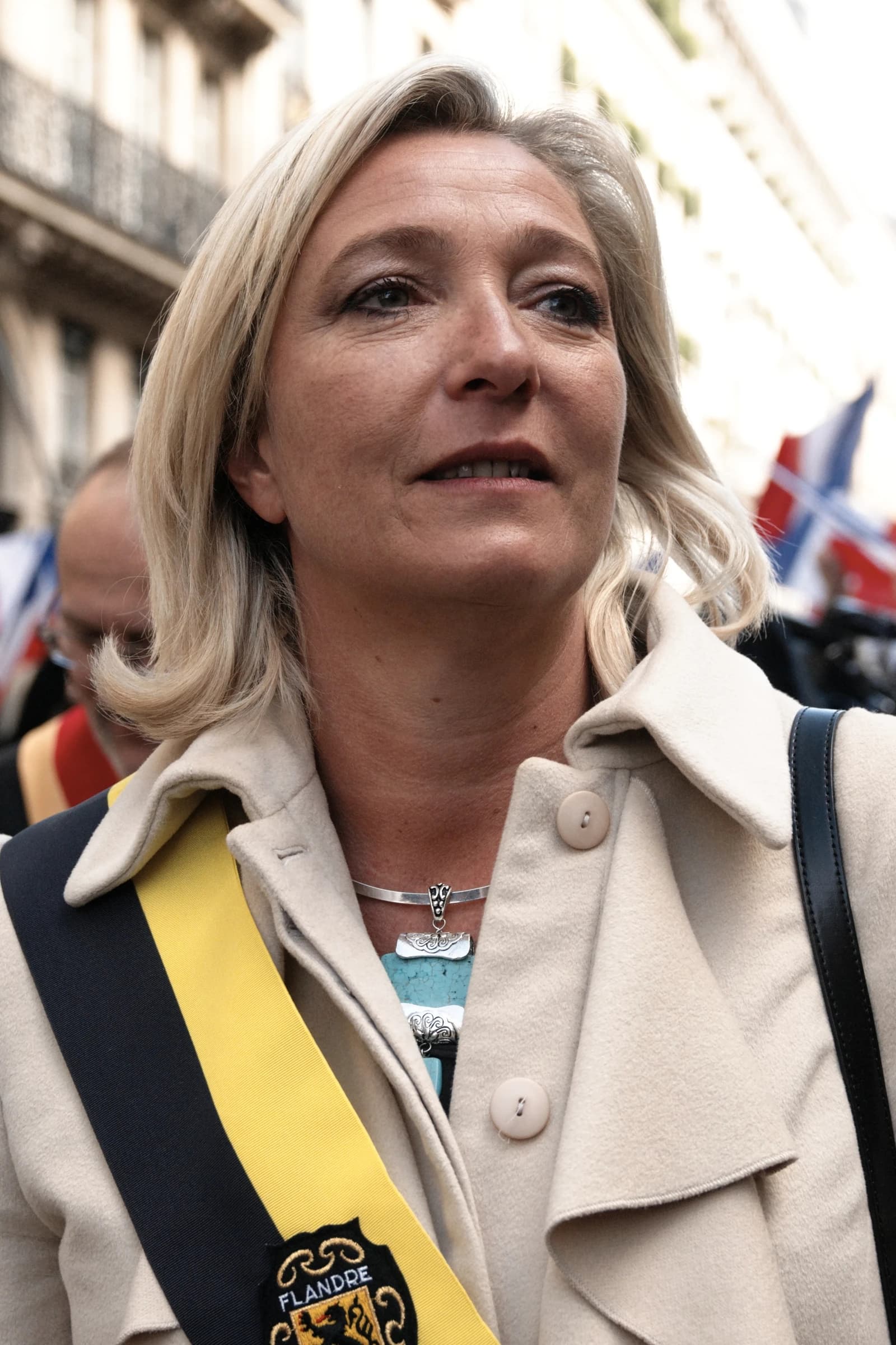 Marine Le Pen, French politician, looking to the right outdoors.