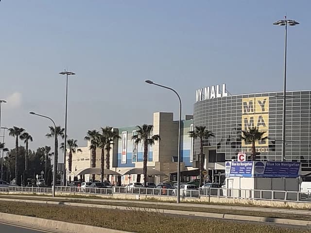 Exterior view of My Mall Limassol in Cyprus, showing the building and a parking area.