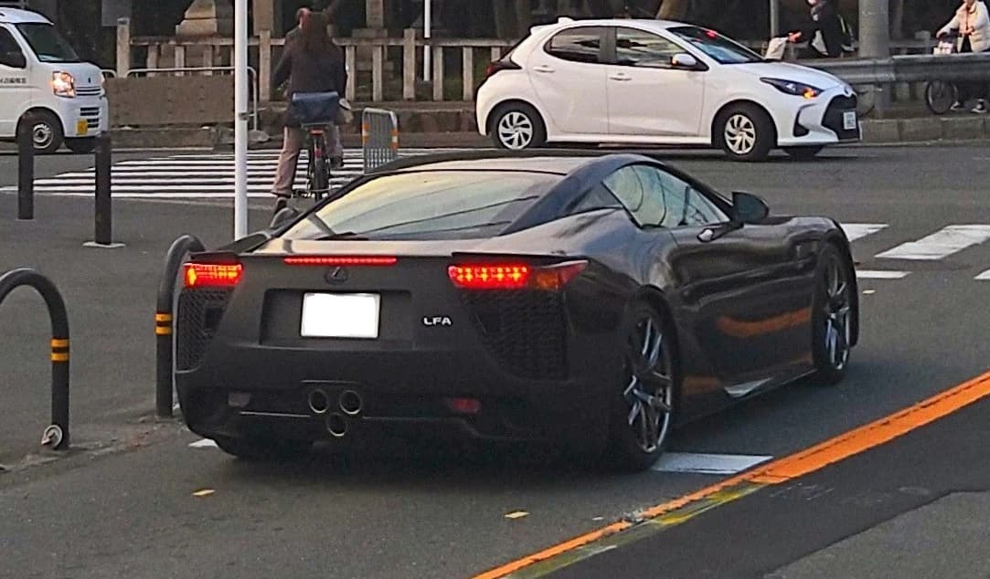 Rear view of a black Lexus LFA sports car on a city street.