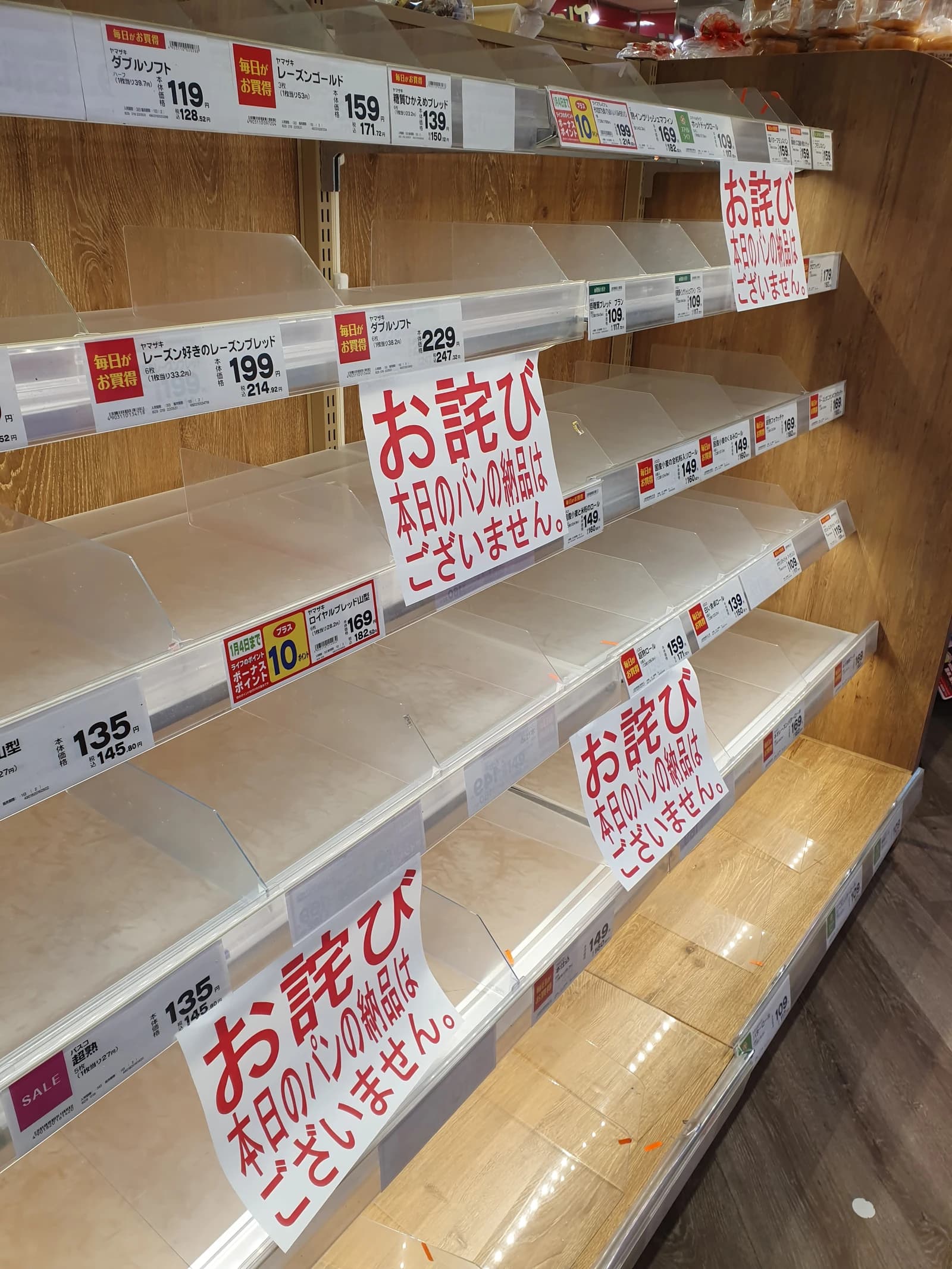Empty bread shelves in a Japanese supermarket with signs indicating no bread available.