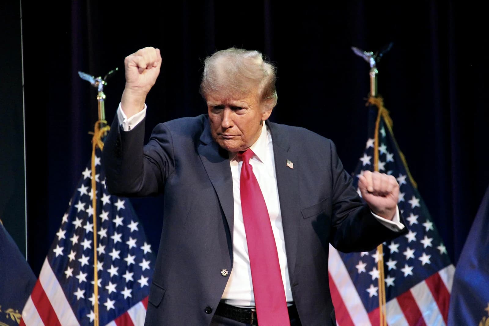 Former President Donald Trump gestures with raised fists at a campaign rally.