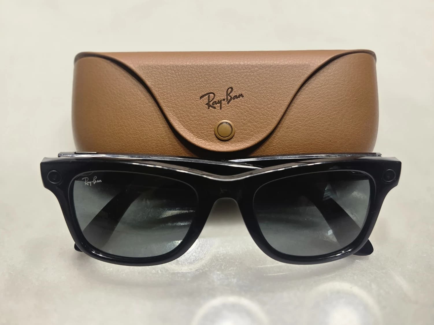 Black Ray-Ban Meta smart glasses with their brown charging case.