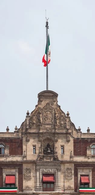 Mexican flag flying above the main balcony of the National Palace in Mexico City.