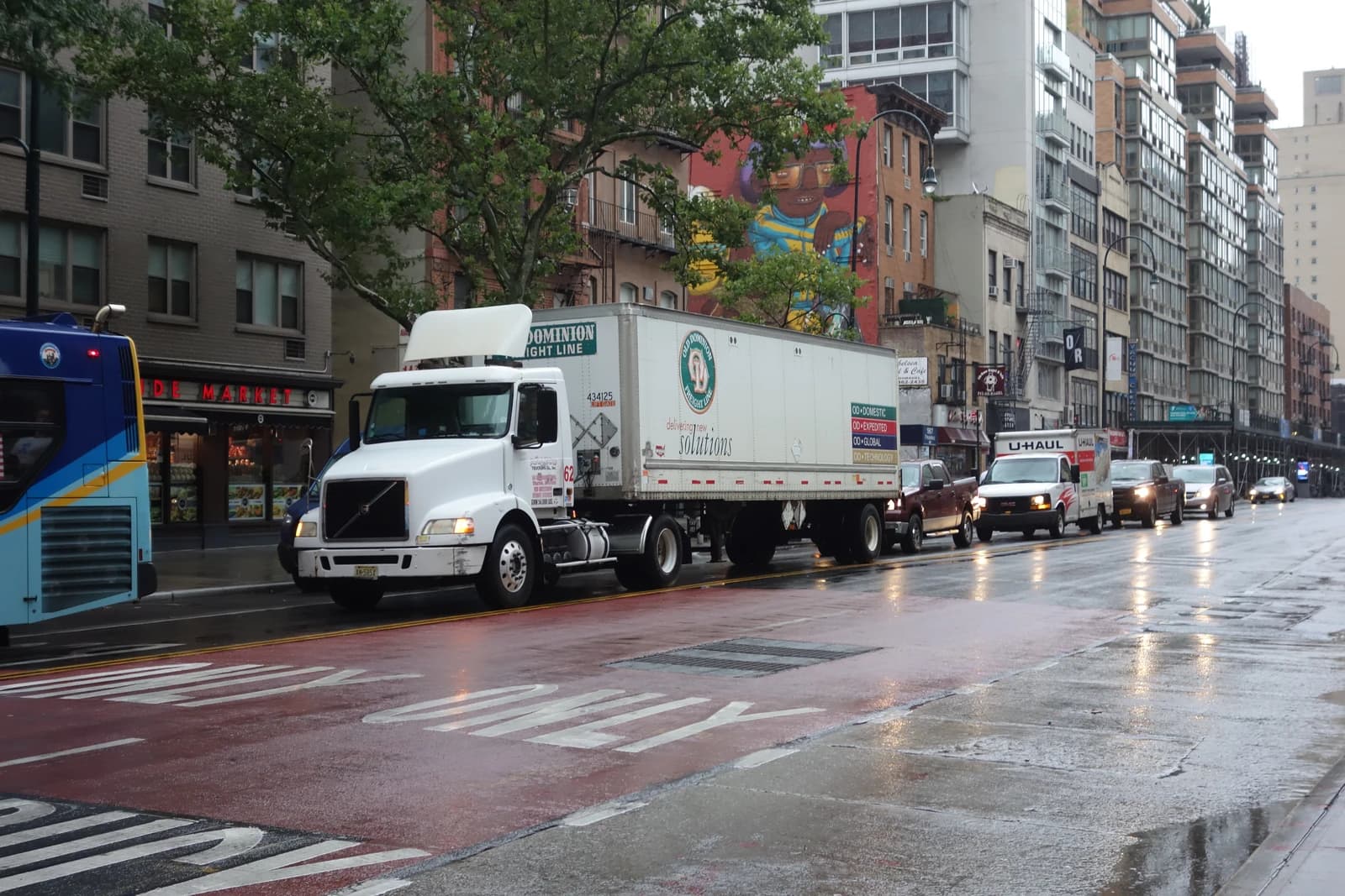An Old Dominion Freight Line truck with its trailer drives on a wet city street.