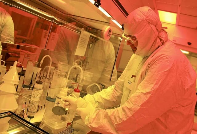 Scientist Phil Evans in a clean room, handling laboratory equipment.