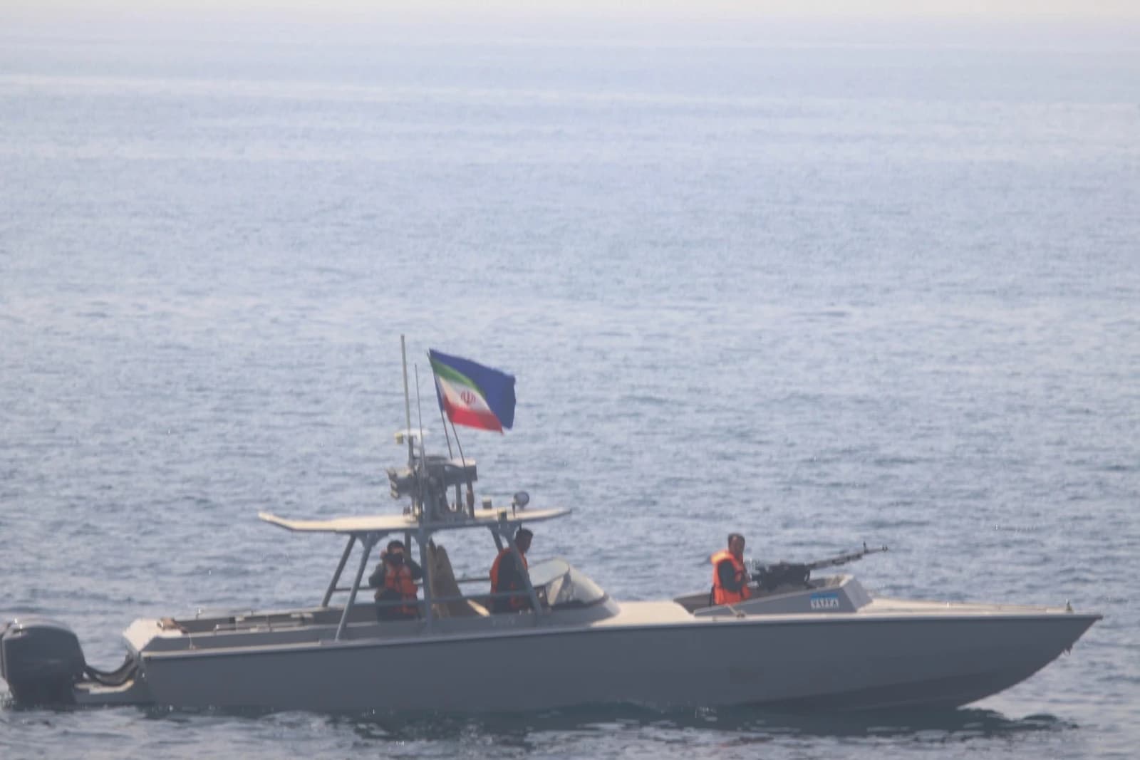 An Iranian Revolutionary Guard Corps speedboat with crew members and an Iranian flag on the water.