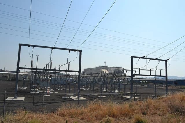 An electrical substation with power lines feeding into a data center building.