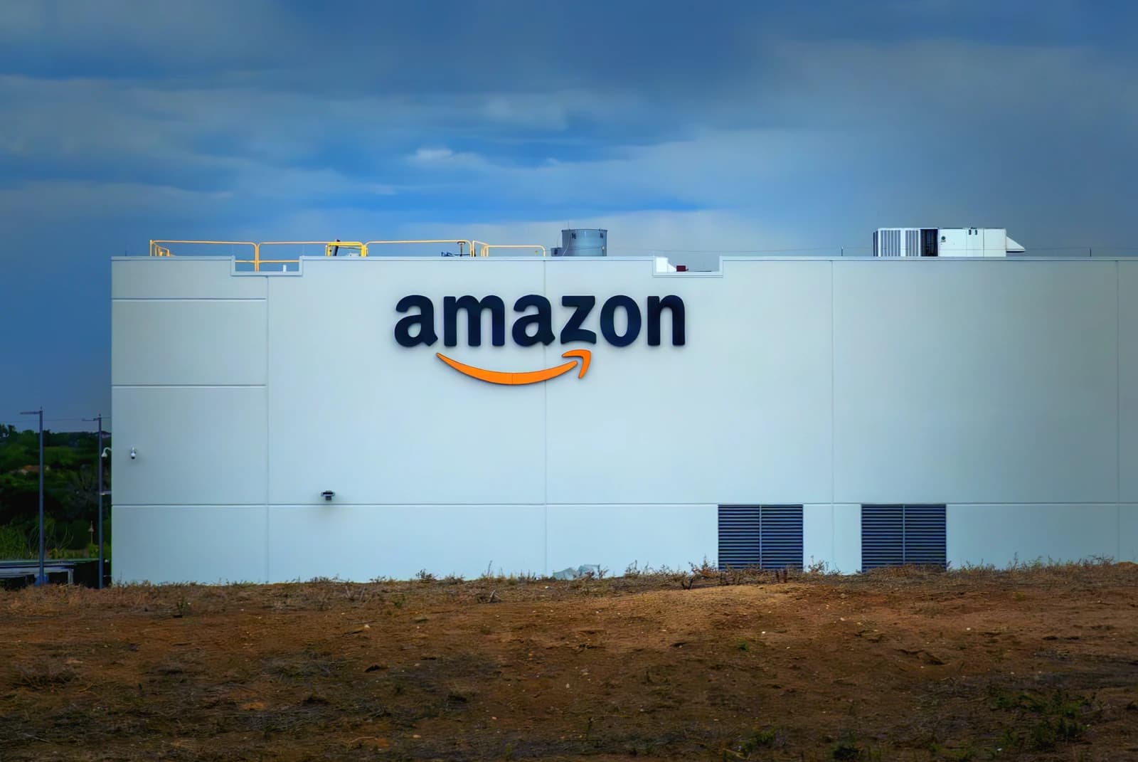 Amazon Fulfillment Center building exterior with large Amazon logo and blue sky.