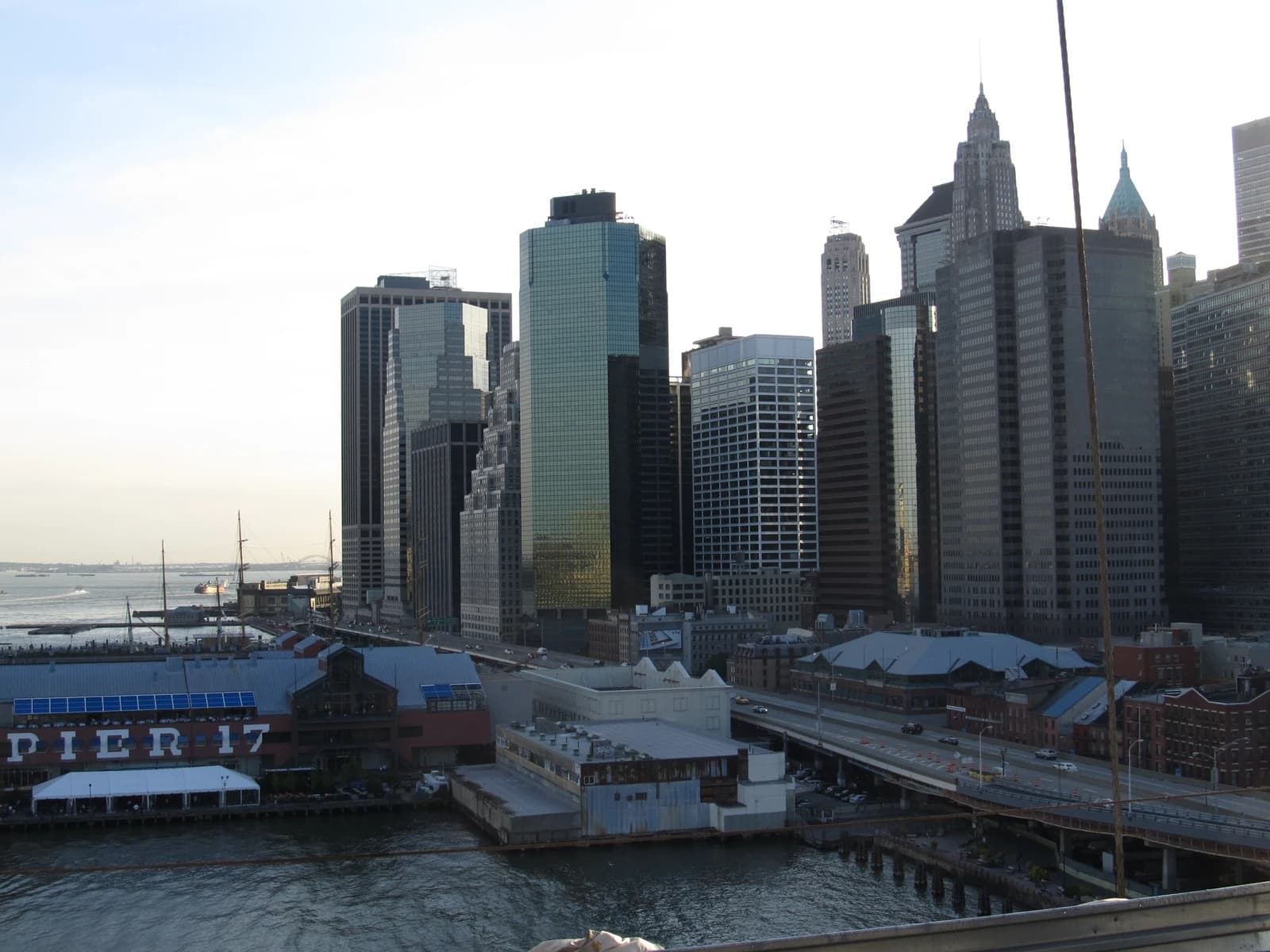Manhattan Financial District skyline and Pier 17 building seen from Brooklyn Bridge.
