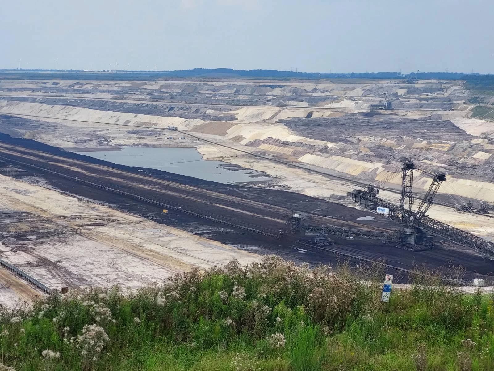 Aerial view of the Inden opencast lignite mine with large machinery and a water body.