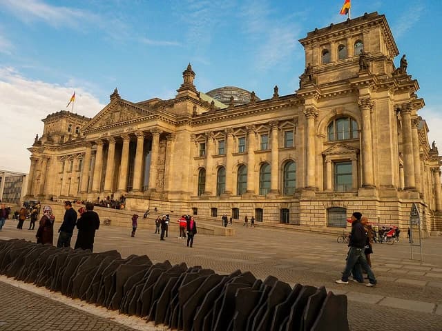 The Reichstag building in Berlin, Germany, with a blue sky overhead.