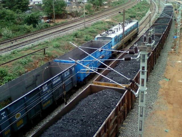 An overhead view of a WAG-7 locomotive pulling open freight cars filled with coal.