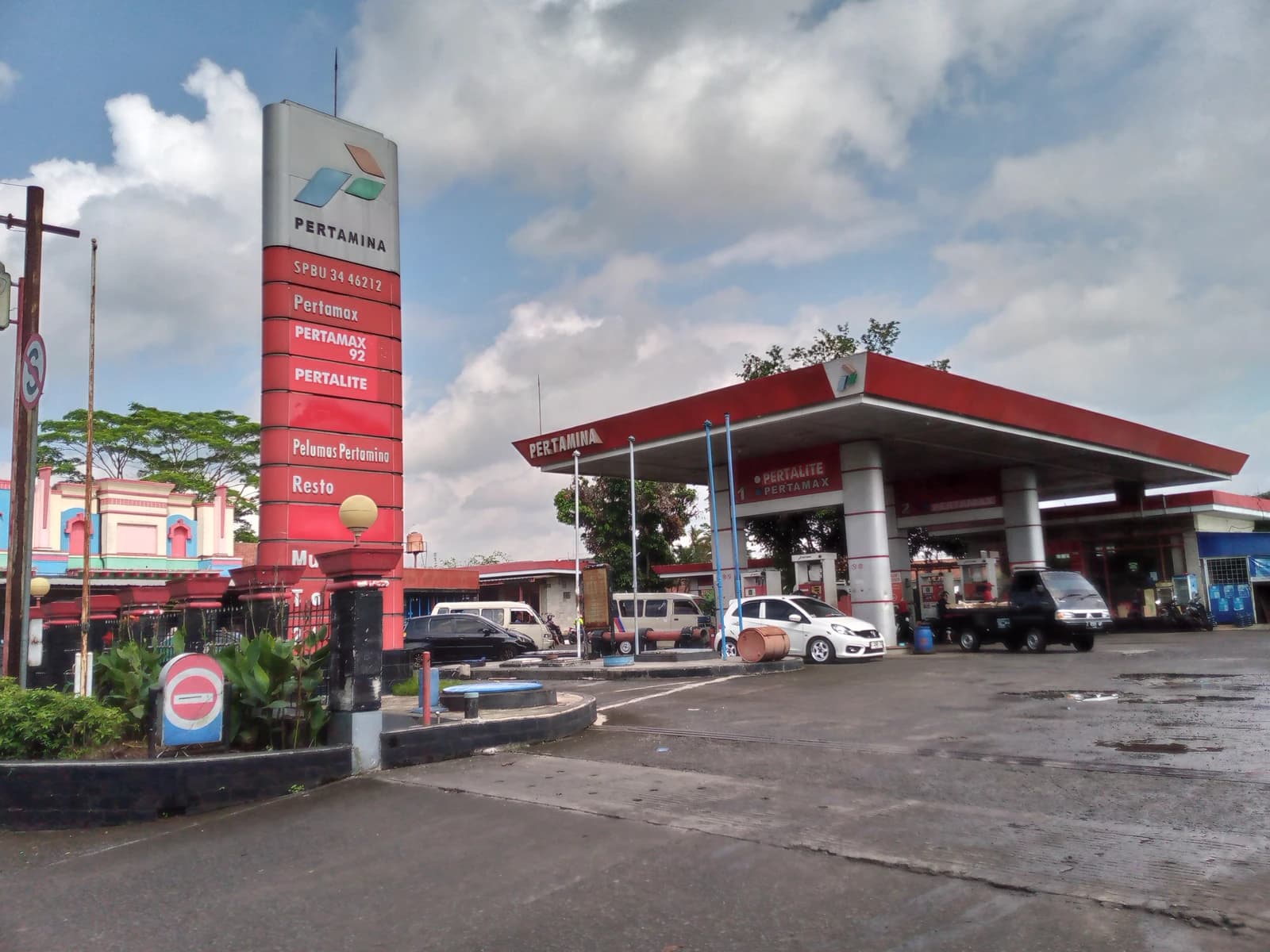 Pertamina gas station with cars parked and under canopy, a large sign to the left.