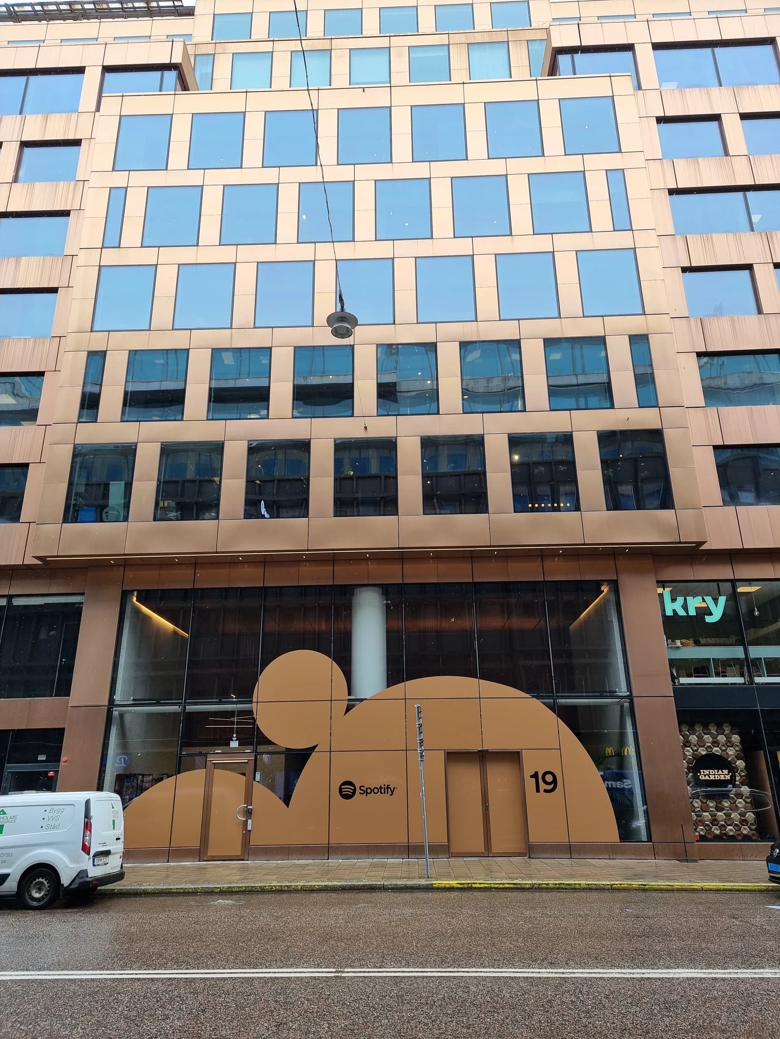 Exterior of modern corporate building featuring Spotify logo prominently on ground floor.
