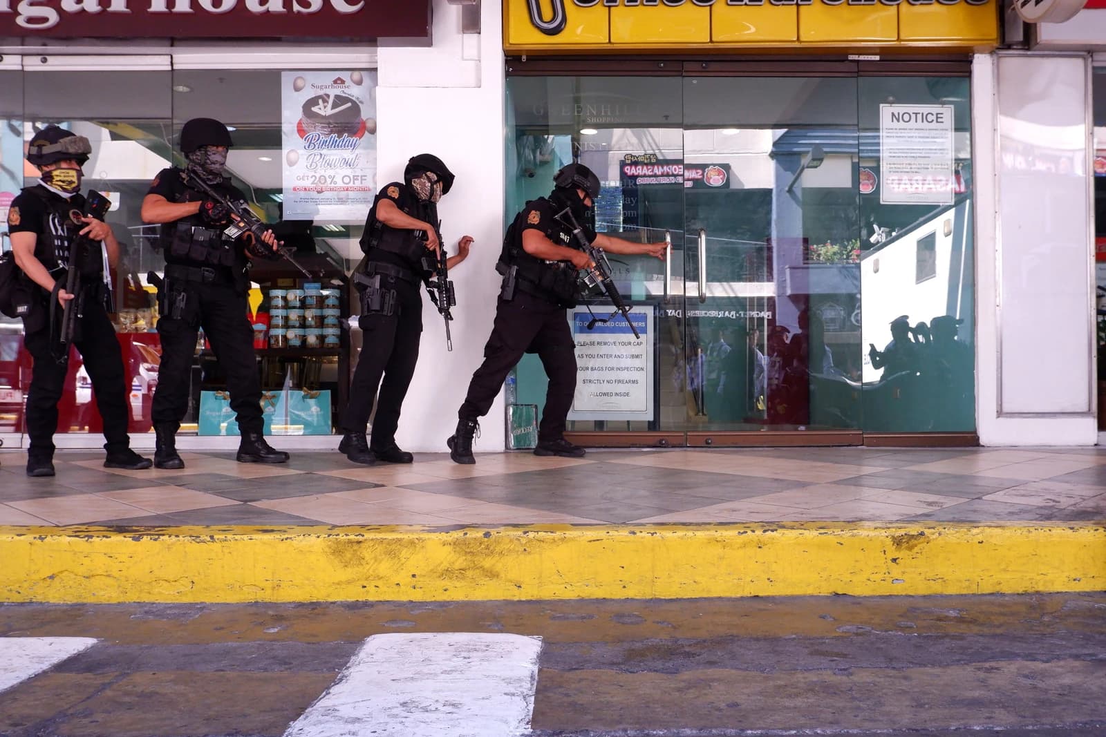 Police Special Weapons and Tactics officers entering Greenhills Shopping Center during an incident.