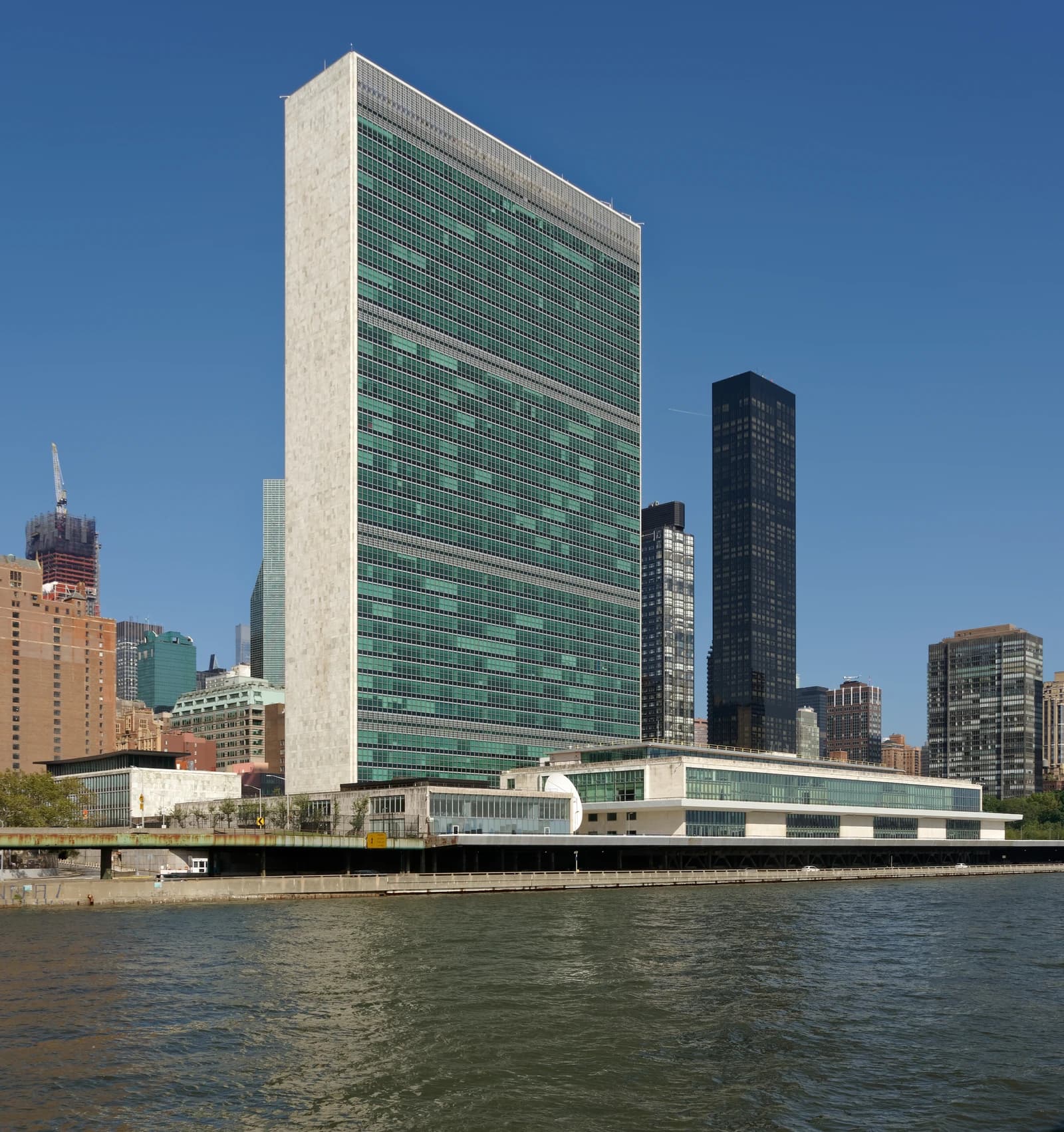The United Nations Headquarters building in New York City with a river in the foreground.