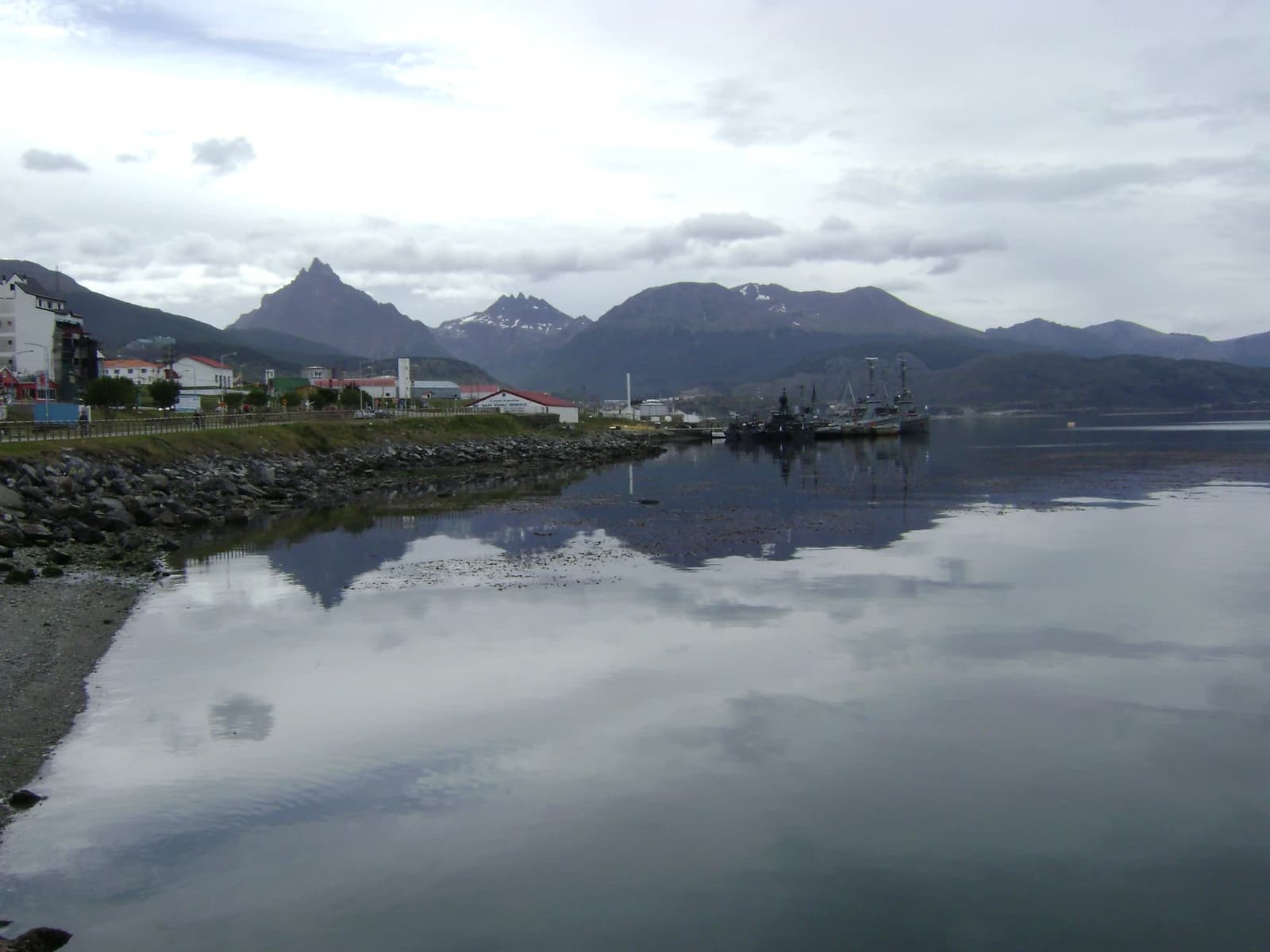 Ushuaia port in Argentina with docked ships, buildings, and mountains in the background.