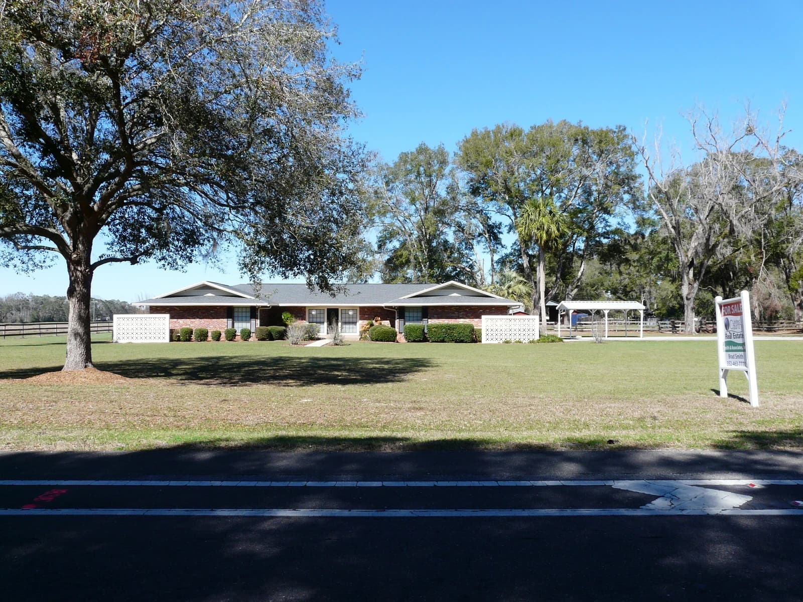 Single story brick house in Florida with a 'For Sale' sign in the yard.