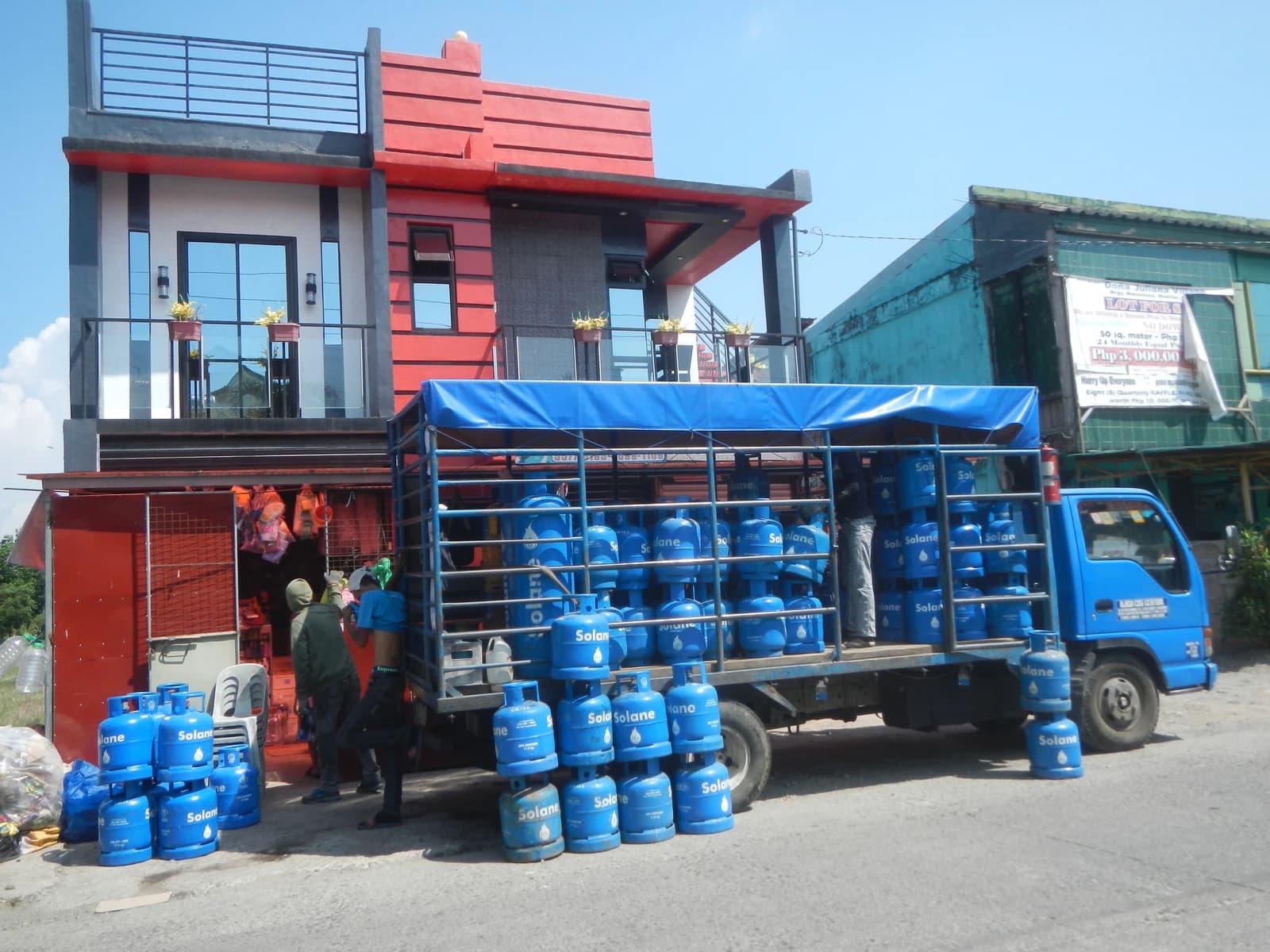 Men unload blue Solane LPG cylinders from a truck in Mabitac, Laguna, Philippines.