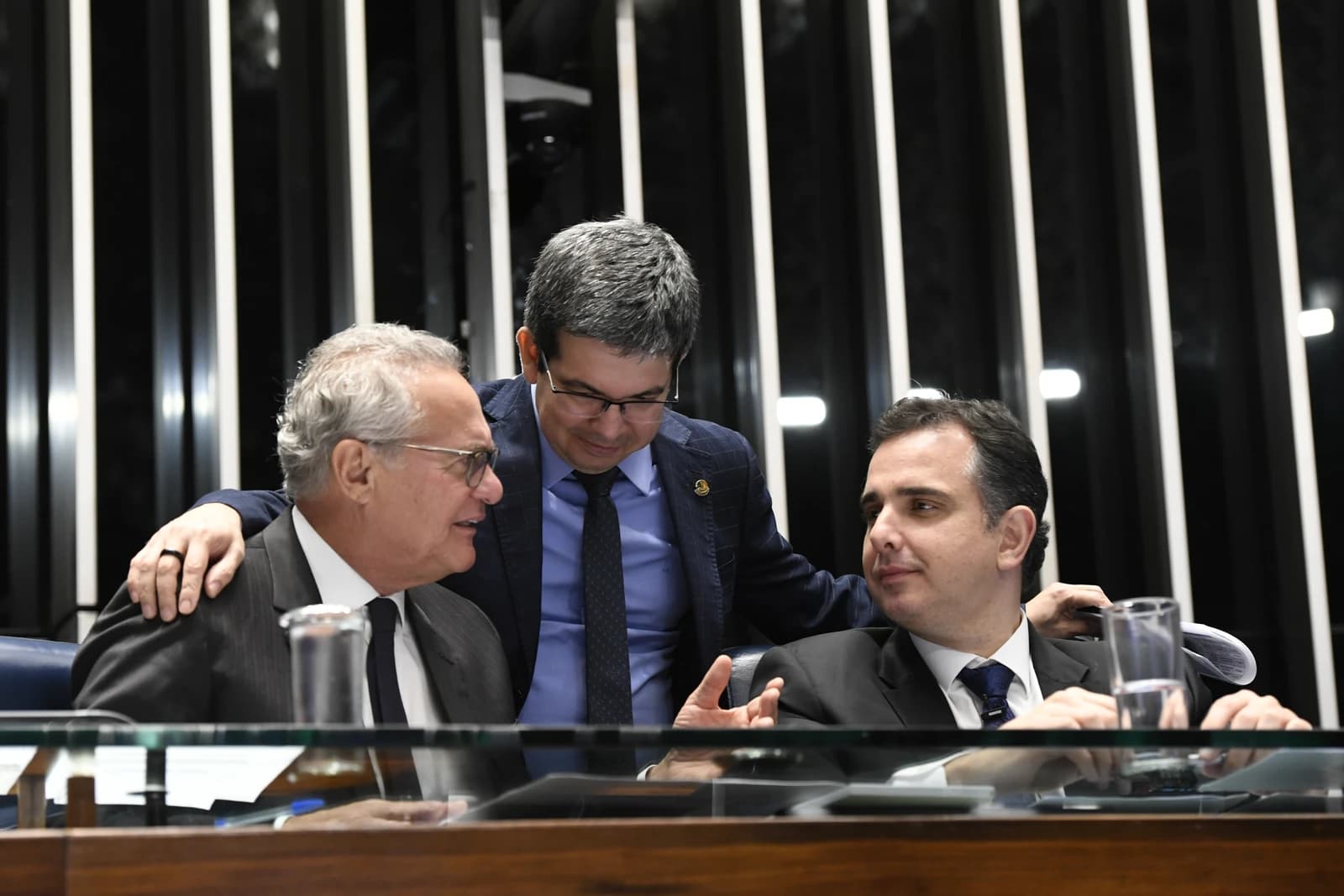 Renan Calheiros, Randolfe Rodrigues, and Rodrigo Pacheco are conversing in a legislative setting.