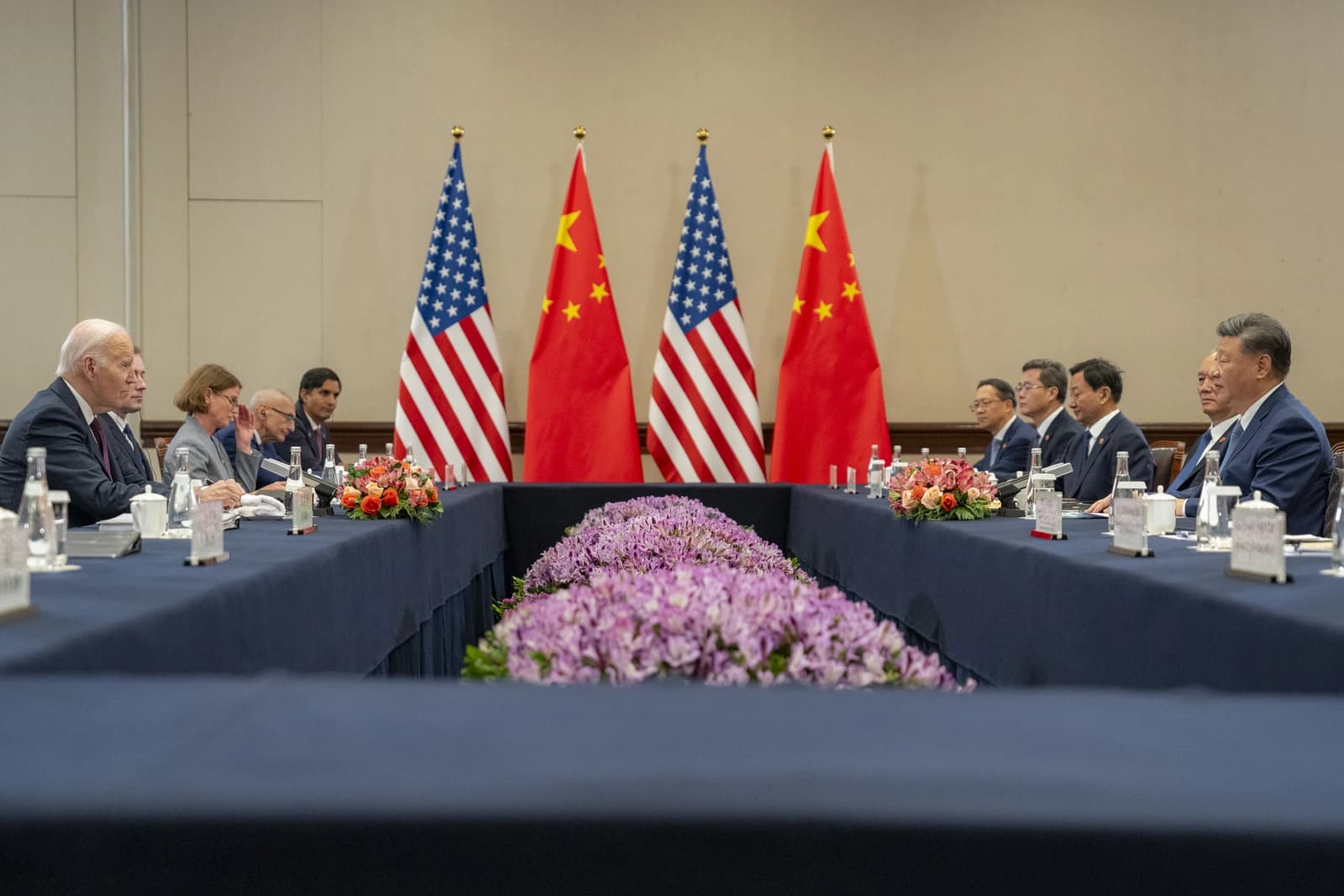 US President Joe Biden and Chinese President Xi Jinping sit across a table.