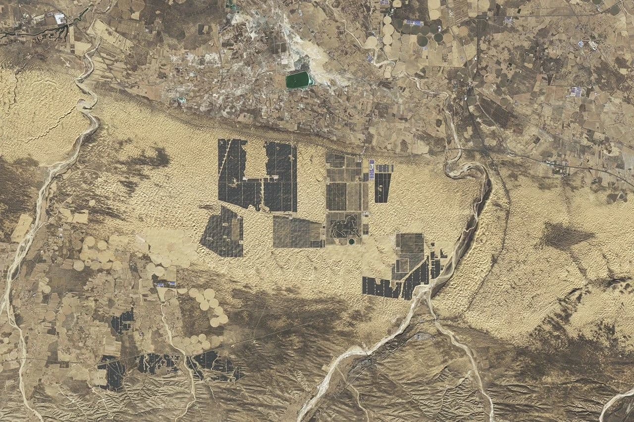 Aerial view shows extensive solar panel installations covering large areas of a desert in China.