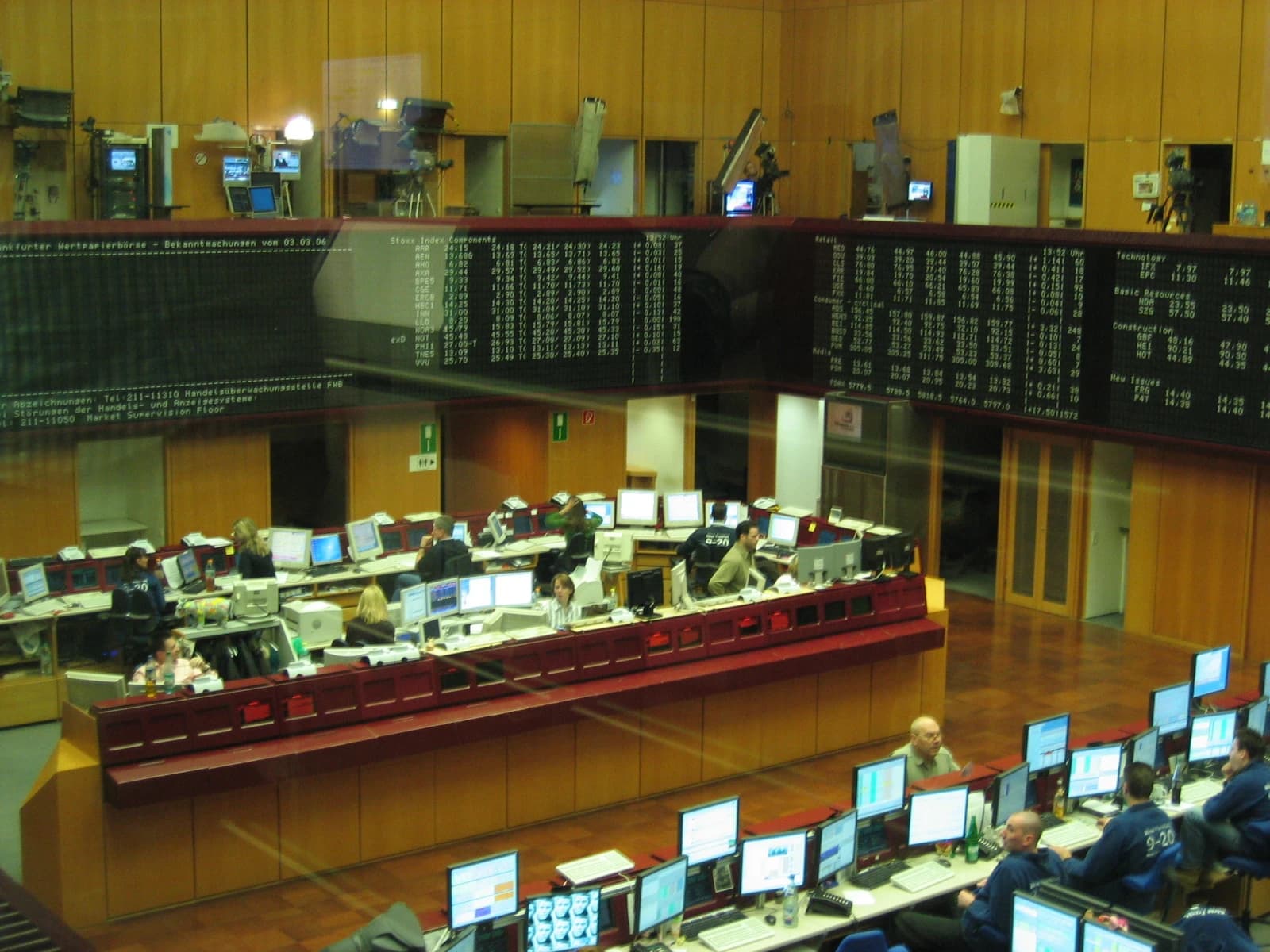 People sitting at desks with multiple computer monitors displaying financial data at a stock exchange.